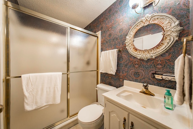 bathroom featuring a textured ceiling, vanity, toilet, and a shower with door