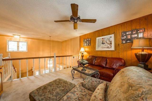 carpeted living room with ceiling fan, a textured ceiling, and wood walls