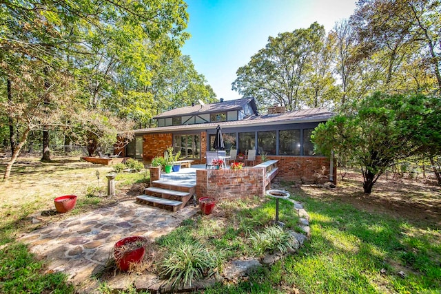 rear view of property with a sunroom and a patio area