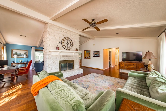 living room with lofted ceiling with beams, a fireplace, a textured ceiling, ceiling fan, and dark hardwood / wood-style floors