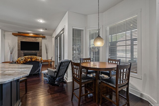 dining space featuring a fireplace and dark wood-type flooring