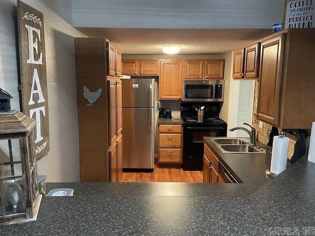 kitchen with a textured ceiling, light hardwood / wood-style floors, sink, and stainless steel appliances