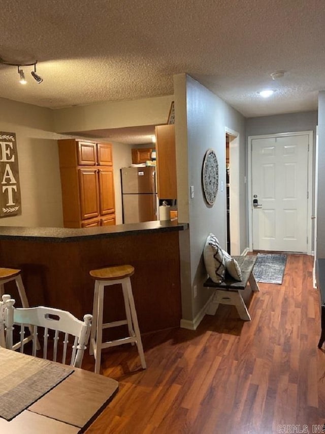 kitchen featuring a textured ceiling, stainless steel fridge, and dark hardwood / wood-style floors