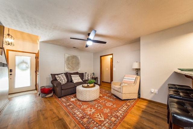 living room featuring ceiling fan with notable chandelier, a textured ceiling, and hardwood / wood-style floors