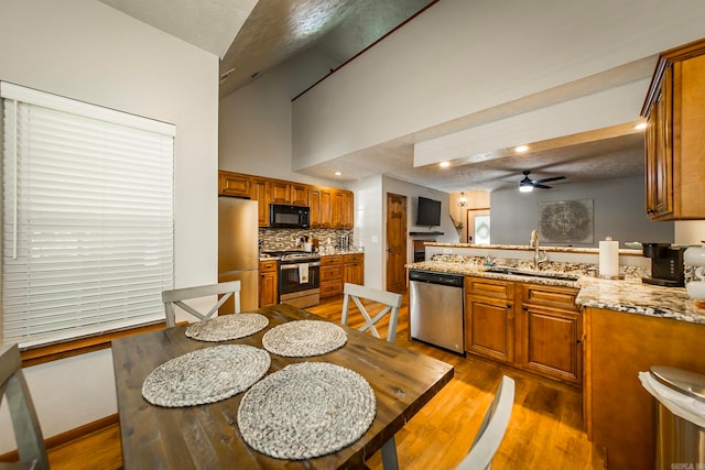 kitchen featuring a textured ceiling, sink, vaulted ceiling, appliances with stainless steel finishes, and ceiling fan