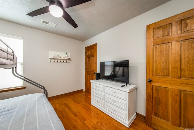 bedroom featuring light hardwood / wood-style flooring, ceiling fan, and a textured ceiling