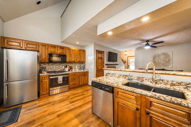 kitchen with a textured ceiling, sink, light hardwood / wood-style flooring, stainless steel appliances, and ceiling fan