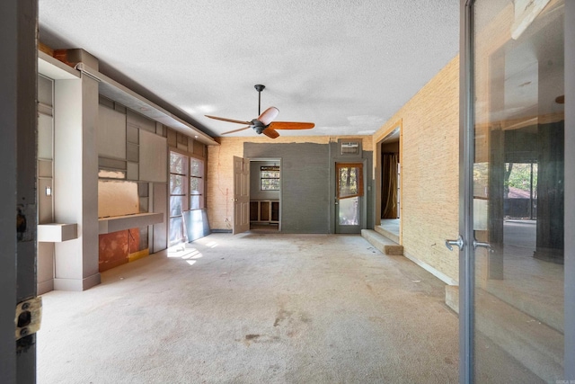 unfurnished living room featuring plenty of natural light, ceiling fan, and carpet floors