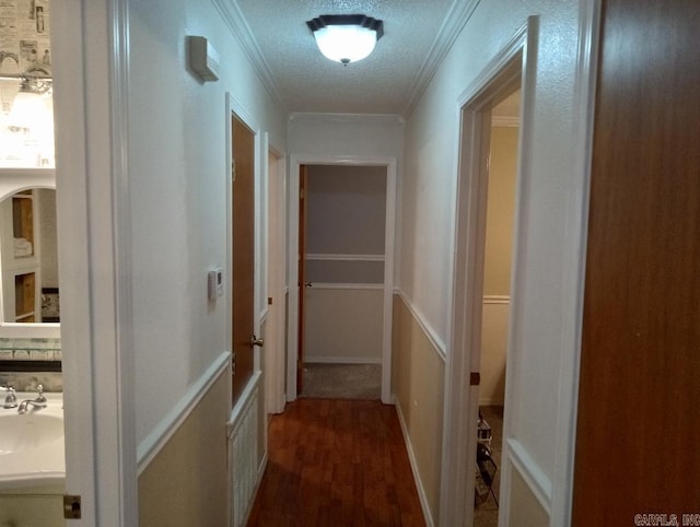 hall with a textured ceiling, ornamental molding, and dark hardwood / wood-style floors