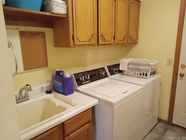 washroom with cabinets, washer and clothes dryer, and sink