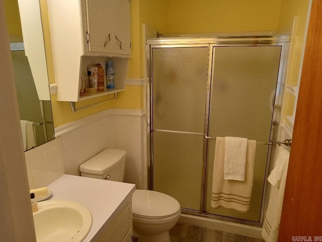 bathroom with wood-type flooring, vanity, toilet, and an enclosed shower