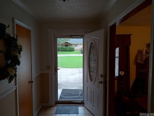 foyer entrance with ornamental molding, a textured ceiling, and light tile patterned floors