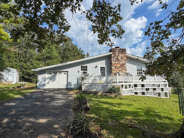 view of front of house with a garage, a wooden deck, and a front lawn