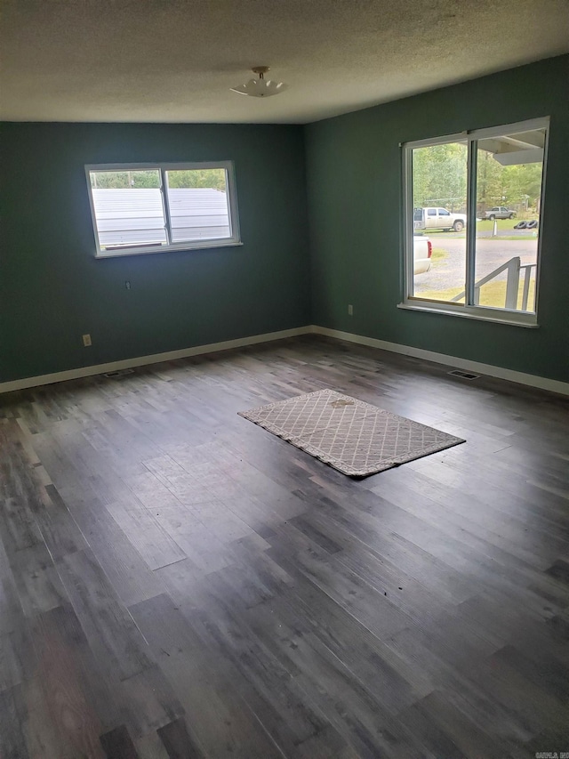 unfurnished room featuring a textured ceiling and dark hardwood / wood-style flooring