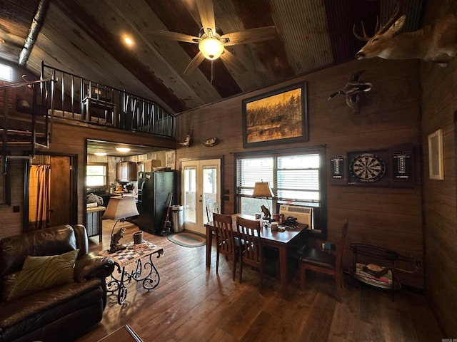 dining room featuring high vaulted ceiling, wooden walls, ceiling fan, and hardwood / wood-style floors