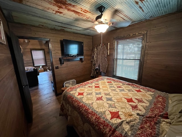 bedroom with wooden walls, ceiling fan, and hardwood / wood-style flooring