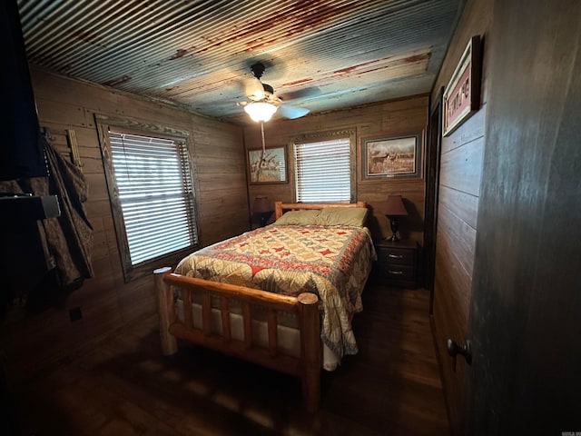 bedroom with wood walls, dark hardwood / wood-style flooring, and ceiling fan