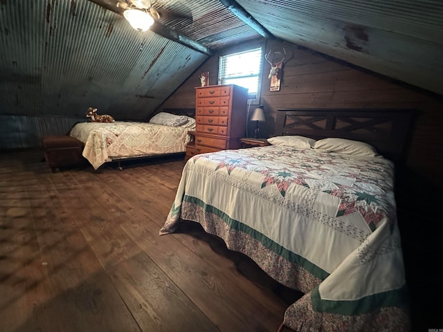 bedroom featuring wooden walls, vaulted ceiling, ceiling fan, and hardwood / wood-style flooring