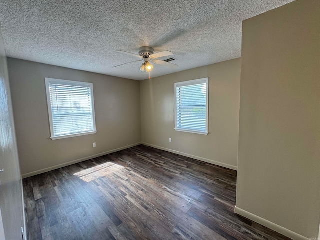 spare room with dark hardwood / wood-style flooring, ceiling fan, a textured ceiling, and a healthy amount of sunlight