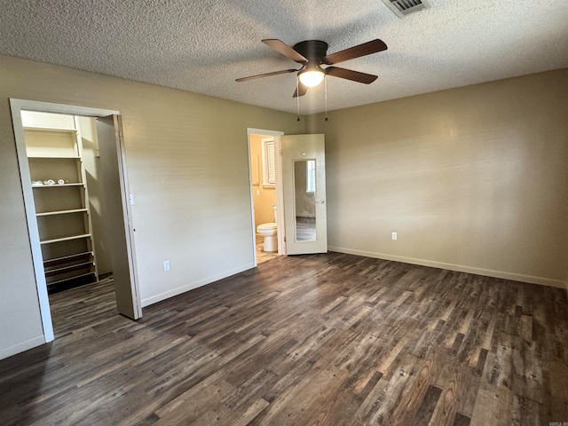 unfurnished bedroom featuring a closet, dark hardwood / wood-style floors, ensuite bath, and a textured ceiling