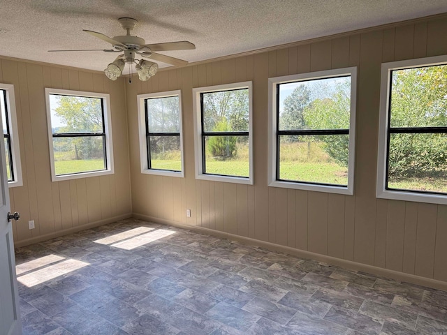 unfurnished sunroom featuring ceiling fan and a healthy amount of sunlight