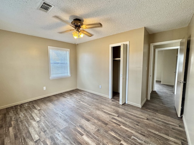 unfurnished bedroom with ceiling fan, dark hardwood / wood-style flooring, a closet, and a textured ceiling