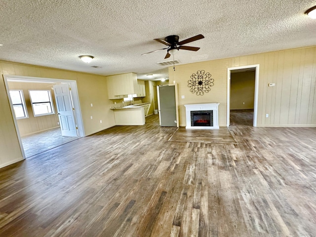 unfurnished living room with hardwood / wood-style floors, a textured ceiling, and ceiling fan