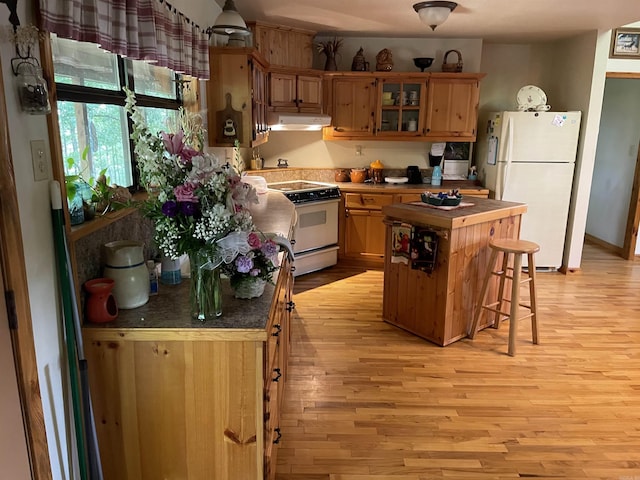 kitchen featuring a kitchen breakfast bar, white appliances, a center island, and light hardwood / wood-style flooring