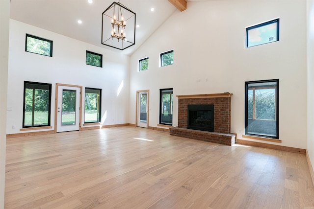 unfurnished living room with beamed ceiling, a healthy amount of sunlight, high vaulted ceiling, and light wood-type flooring