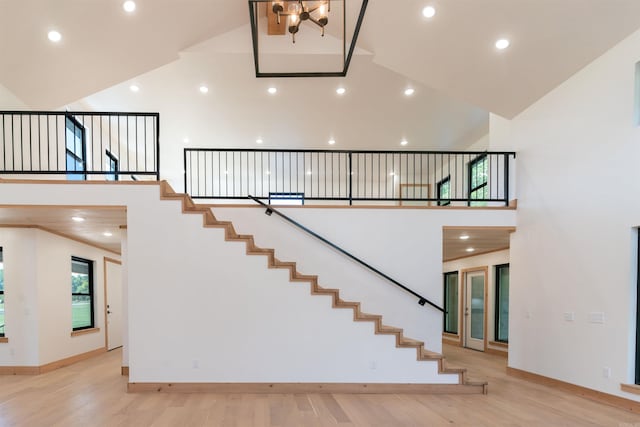 stairway with hardwood / wood-style flooring and high vaulted ceiling