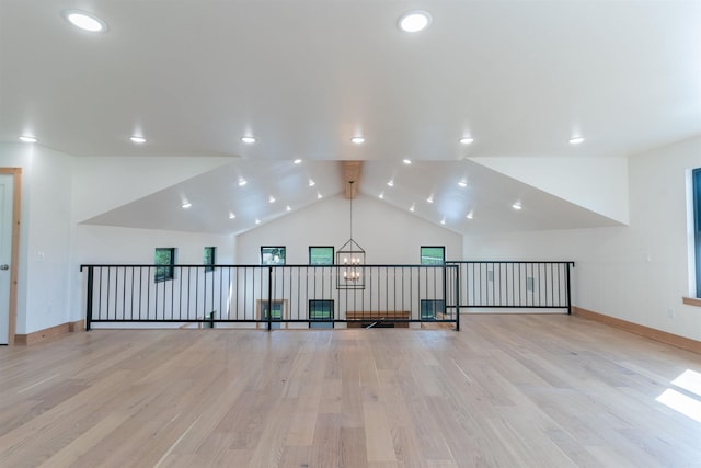 additional living space featuring vaulted ceiling, a notable chandelier, and light hardwood / wood-style floors