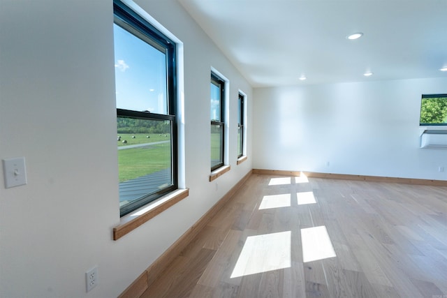 spare room featuring a healthy amount of sunlight, cooling unit, and light wood-type flooring