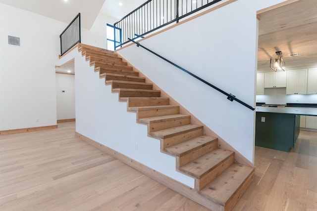 stairway with a towering ceiling and hardwood / wood-style flooring