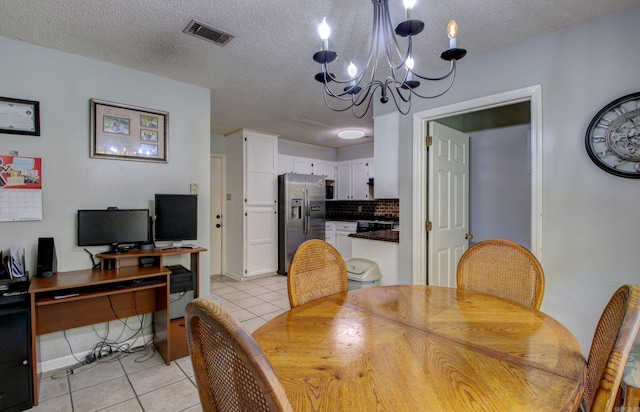 tiled dining area featuring an inviting chandelier and a textured ceiling