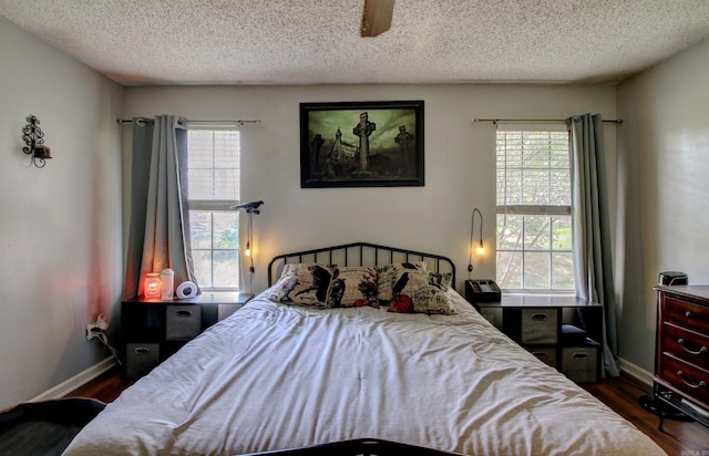 bedroom with ceiling fan, a textured ceiling, and dark hardwood / wood-style flooring