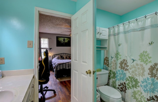 bathroom featuring a textured ceiling, wood-type flooring, vanity, and toilet