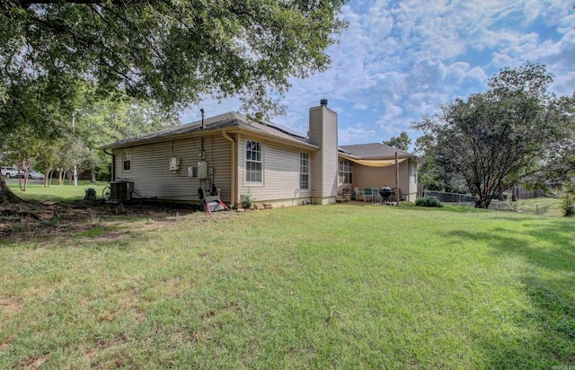 rear view of house featuring a lawn and central AC