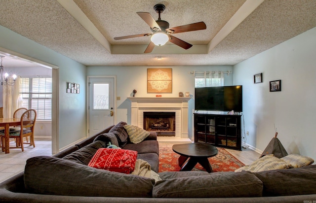 living room featuring ceiling fan with notable chandelier, plenty of natural light, light tile patterned floors, and a fireplace