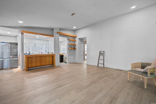 interior space with light wood-type flooring, stainless steel refrigerator, and lofted ceiling