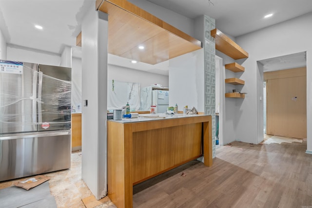 kitchen with white refrigerator, light hardwood / wood-style floors, stainless steel refrigerator, and tasteful backsplash