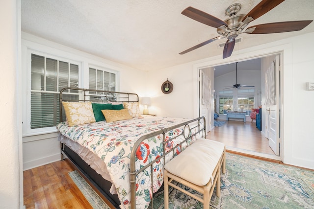 bedroom featuring lofted ceiling, ceiling fan, hardwood / wood-style floors, and a textured ceiling