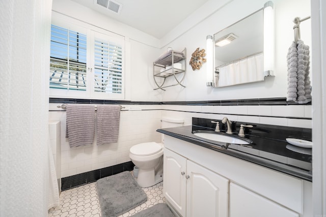 bathroom with tile walls, tile patterned flooring, vanity, and toilet