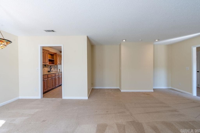 carpeted empty room with a textured ceiling and sink