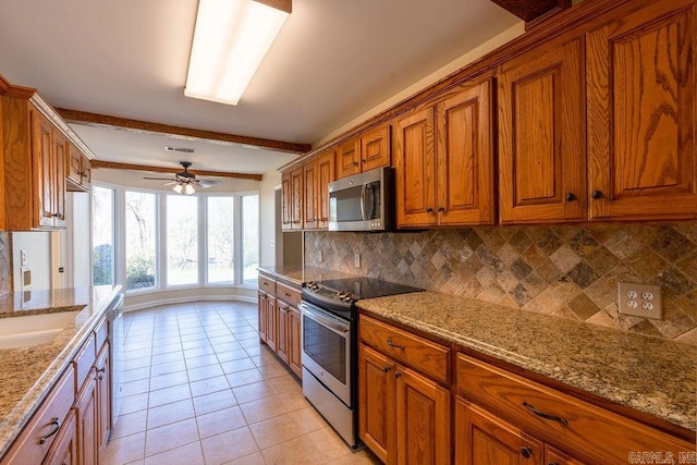 kitchen featuring appliances with stainless steel finishes, beam ceiling, light stone countertops, and ceiling fan