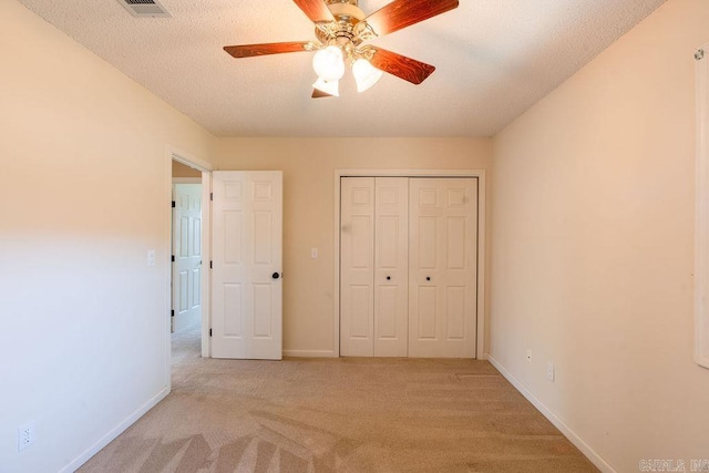 unfurnished bedroom with a textured ceiling, light carpet, ceiling fan, and a closet