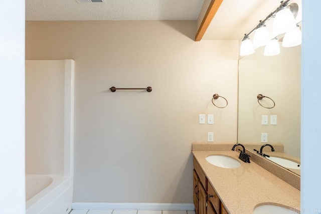 bathroom featuring a bath, a textured ceiling, vanity, and tile patterned flooring