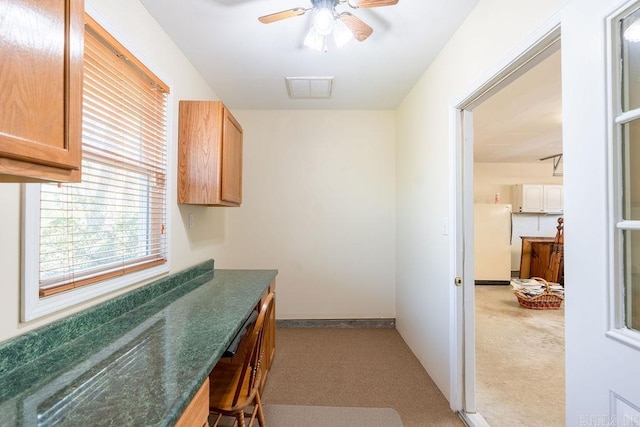 kitchen featuring ceiling fan, light colored carpet, and white fridge