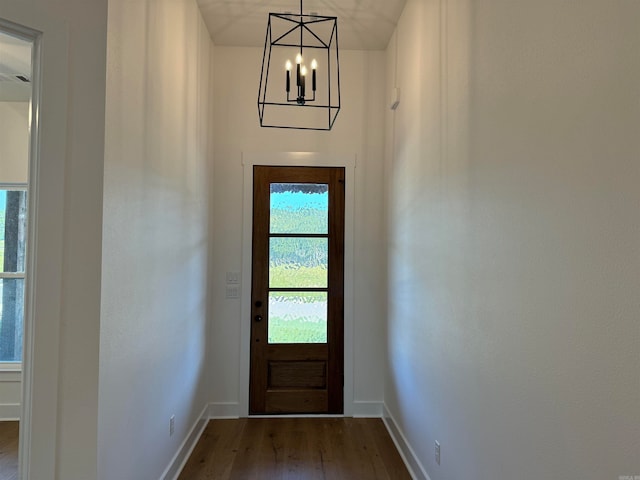 doorway to outside with a chandelier and dark wood-type flooring