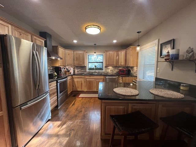 kitchen featuring a textured ceiling, dark hardwood / wood-style floors, wall chimney range hood, stainless steel appliances, and decorative light fixtures