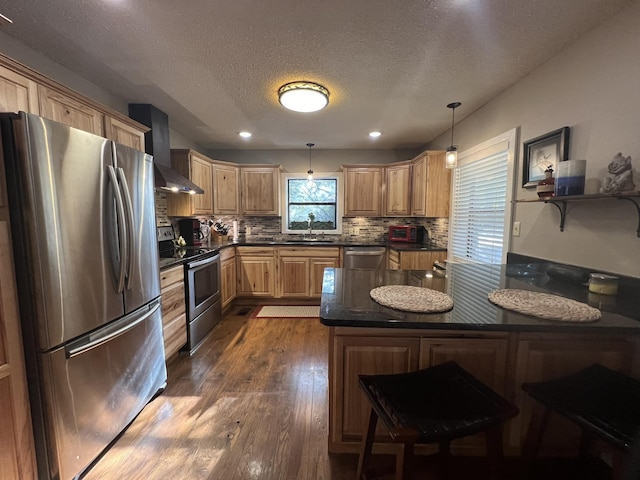 kitchen featuring wall chimney range hood, a sink, stainless steel appliances, decorative backsplash, and dark wood-type flooring